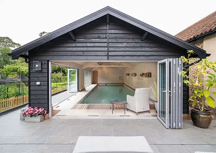 Pool heating heat pump External view from the end of a heated pool lookign through opened bifold doors