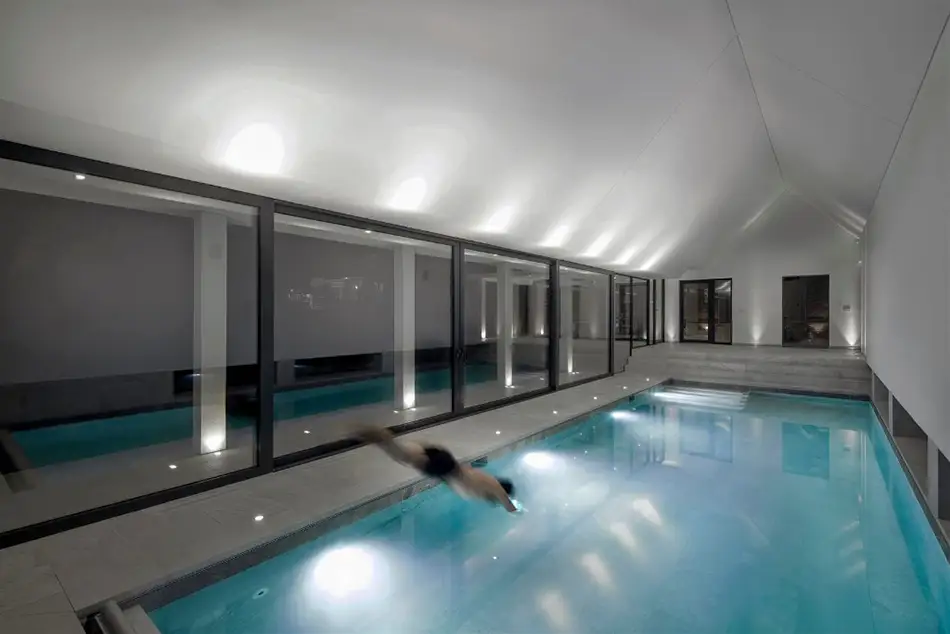 What does an indoor pool really cost in 2026? Man diving into an indoor swimming pool