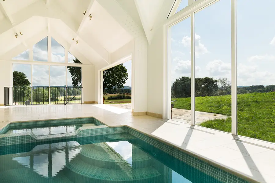 How Indoor Pools Stay Comfortable Year-Round Looking out from a pool house onto a country garden