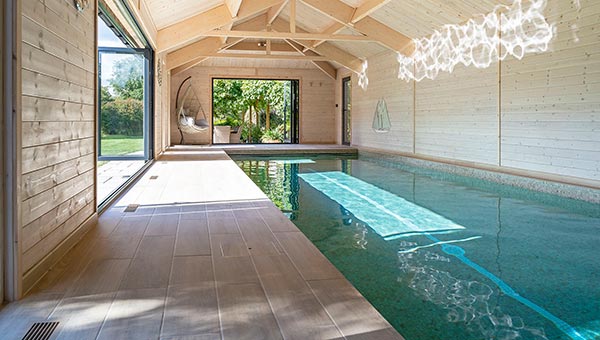 Indoor swimmign pool with bifold doors letting in sunligt