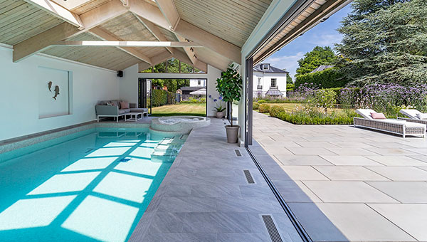 Indoor swimmign pool taken from inside the pool house, on the right the bifold doors are wide open.